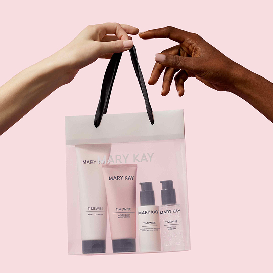 Person handing a bag of Mary Kay Timewise Miracle Set to someone