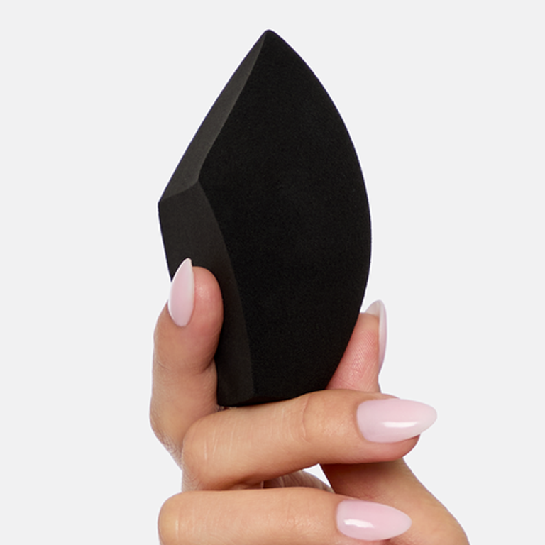 Hand holding a black Mary Kay&reg; Complexion Sponge, highlighting its shape for buffing, blending, and applying makeup.